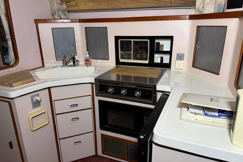 Slide: The Image of 1989 Sea Ray 340 Express Cruiser kitchen with stove, sink, and storage cabinets. - 4