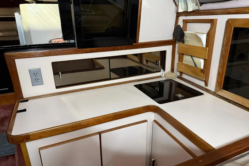 Slide: The Image of 1989 Sea Ray 340 Express Cruiser interior kitchen with stove, cabinets, and wood accents. - 6