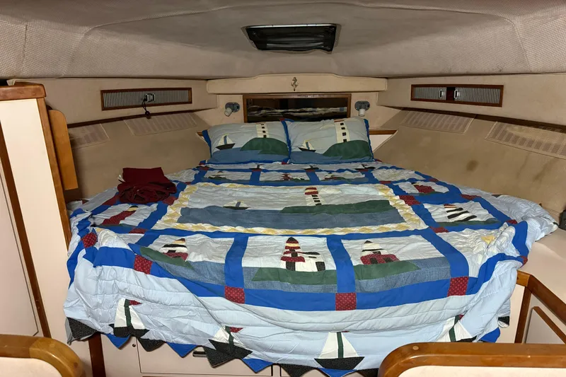Slide: The Image of Cozy cabin interior of 1989 Sea Ray 340 Express Cruiser with nautical-themed bedding. - 8