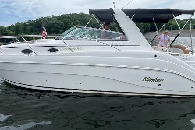 The Image of 2003 Rinker Fiesta Vee 342 boat on water, featuring sleek white design and canopy. - 0