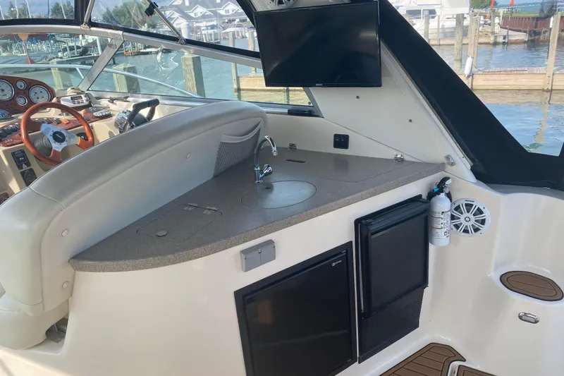 Slide: The Image of 2003 Rinker Fiesta Vee 342 boat interior with helm, sink, and mini fridge. - 4