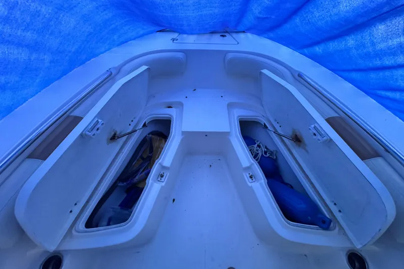 Slide: The Image of 2015 Robalo R200 Center Console boat storage compartments under blue tarp. - 12