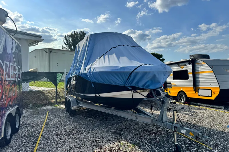 Slide: The Image of 2015 Robalo R200 Center Console boat covered on trailer, parked beside RVs. - 3