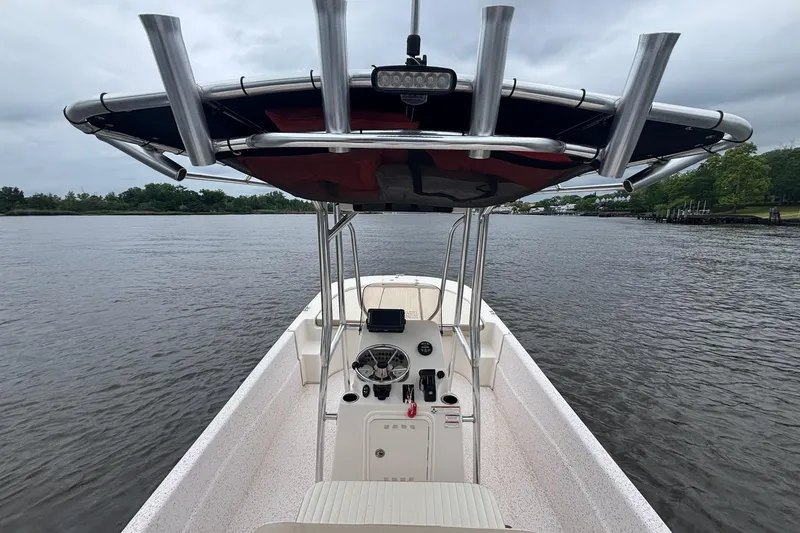 Slide: The Image of 2019 Carolina Skiff 218 DLV boat on calm river, featuring center console and T-top. - 13