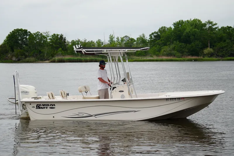 Slide: The Image of 2019 Carolina Skiff 218 DLV boat on calm water with lush green background. - 3