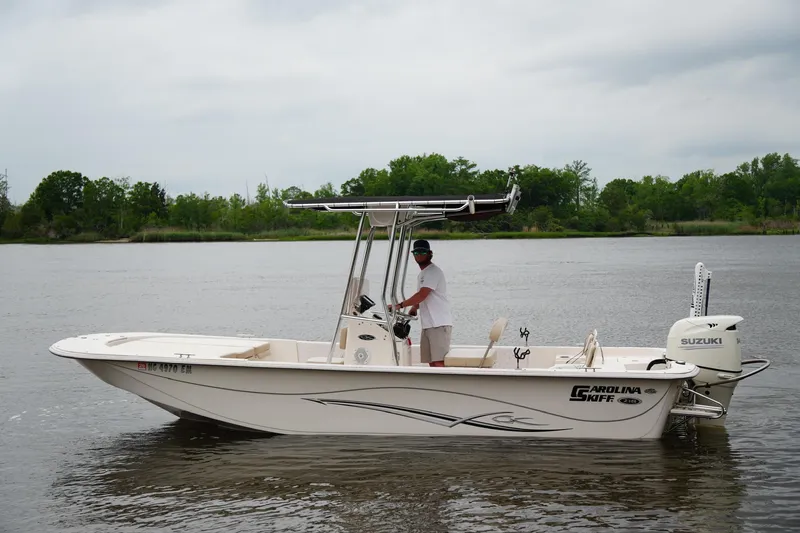 Slide: The Image of 2019 Carolina Skiff 218 DLV boat on a calm river with a person steering. - 5