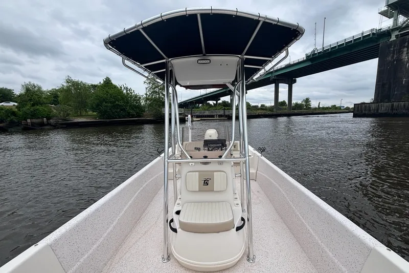 Slide: The Image of 2019 Carolina Skiff 218 DLV boat on a river under a cloudy sky near a bridge. - 8