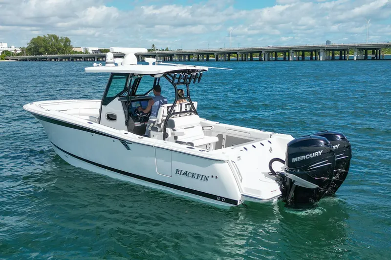 Slide: The Image of 2023 Blackfin 302 CC boat cruising on blue water with twin Mercury engines. - 2