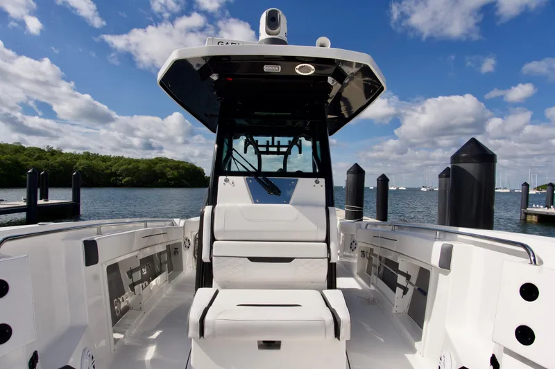 Slide: The Image of 2023 Blackfin 302 CC boat interior with seating, docked by a scenic waterfront. - 20