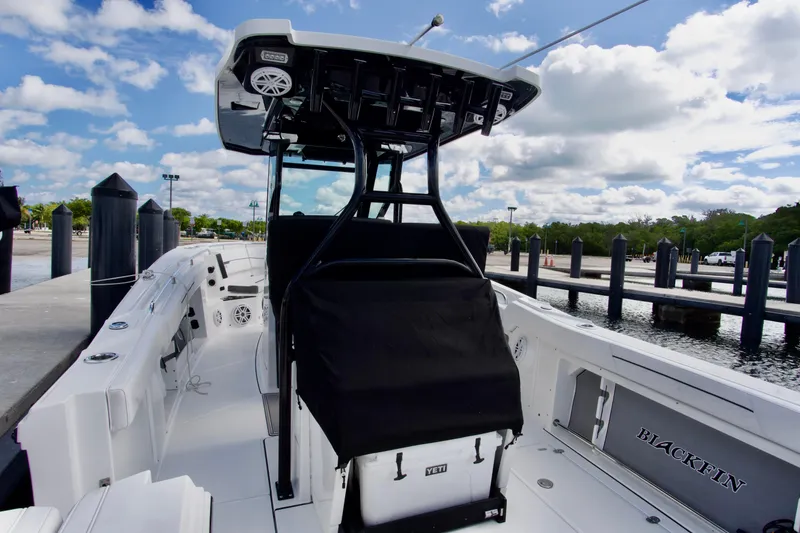 Slide: The Image of 2023 Blackfin 302 CC boat docked, showcasing sleek design and spacious deck under a blue sky. - 28