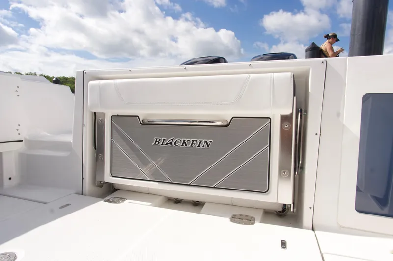 Slide: The Image of 2023 Blackfin 302 CC boat interior detail with branded storage compartment under a blue sky. - 32
