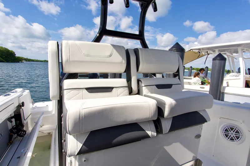 Slide: The Image of 2023 Blackfin 302 CC boat interior with plush seating, docked by a scenic waterway. - 36