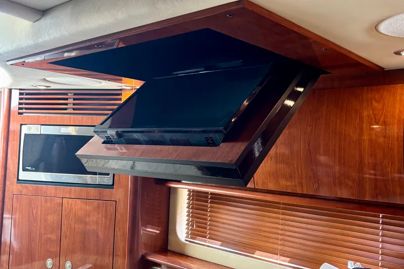 Slide: The Image of 2006 Sea Ray Sundancer 400 interior with retractable TV and wooden cabinetry. - 14