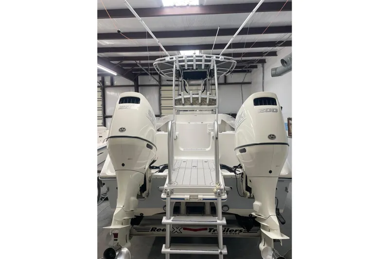 Slide: The Image of 2013 Prowler 25 boat with dual outboard engines in a warehouse setting. - 12