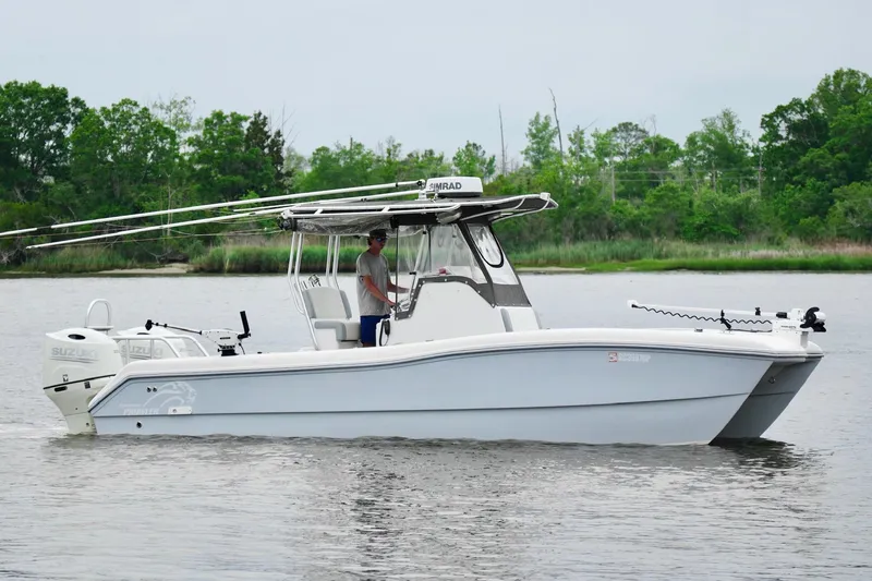 Slide: The Image of 2013 Prowler 25 boat on calm water, featuring dual Suzuki engines and fishing equipment. - 2