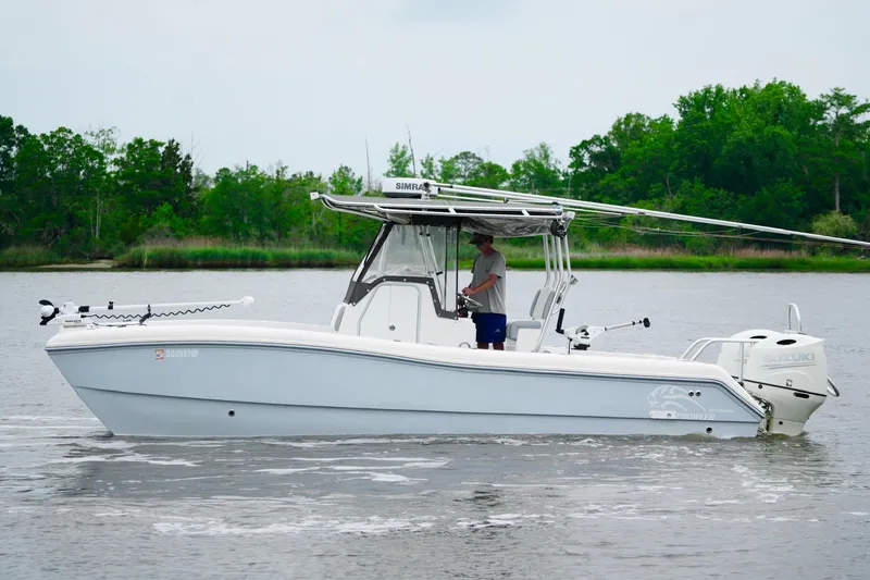 Slide: The Image of 2013 Prowler 25 boat on calm water, with lush green trees in the background. - 5