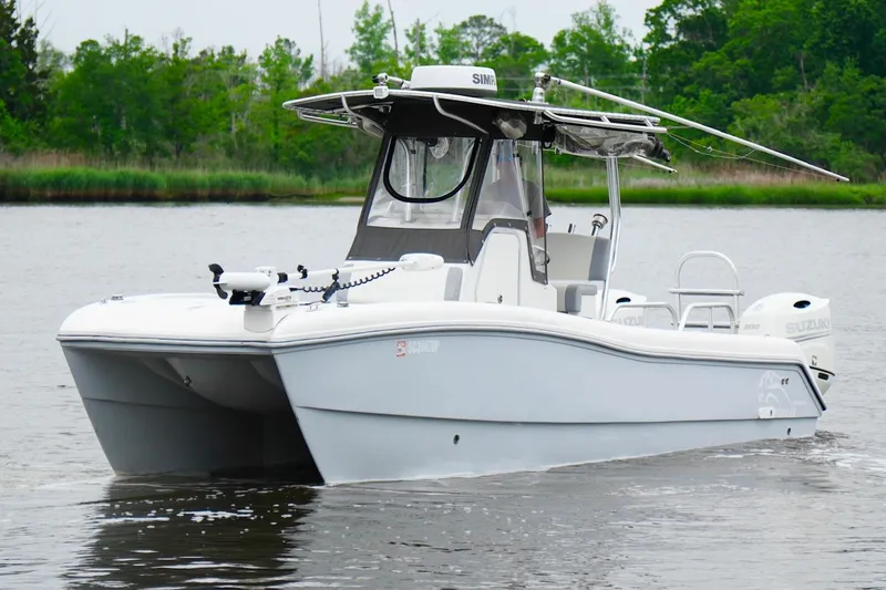 Slide: The Image of 2013 Prowler 25 catamaran boat on calm water, surrounded by lush greenery. - 9