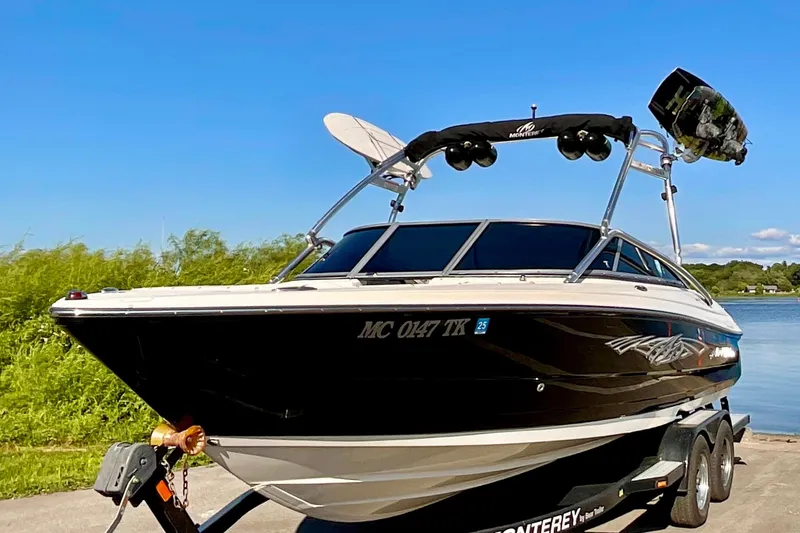 Slide: The Image of 2012 Monterey 224FS boat on trailer by a lake under clear blue sky. - 2