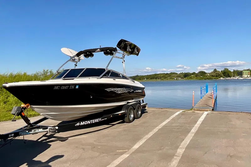Slide: The Image of 2012 Monterey 224FS boat on trailer by a lake under clear blue sky. - 3