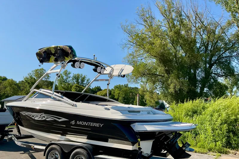 Slide: The Image of 2012 Monterey 224FS boat on trailer, parked outdoors with trees in the background. - 4