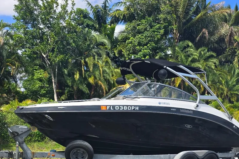 Slide: The Image of 2012 Yamaha Boats 242 Limited S on trailer, surrounded by lush greenery. - 2