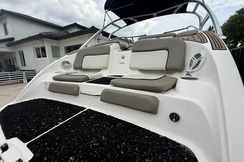 Slide: The Image of 2012 Yamaha Boats 242 Limited S with cushioned seating and speakers, docked near a house. - 7
