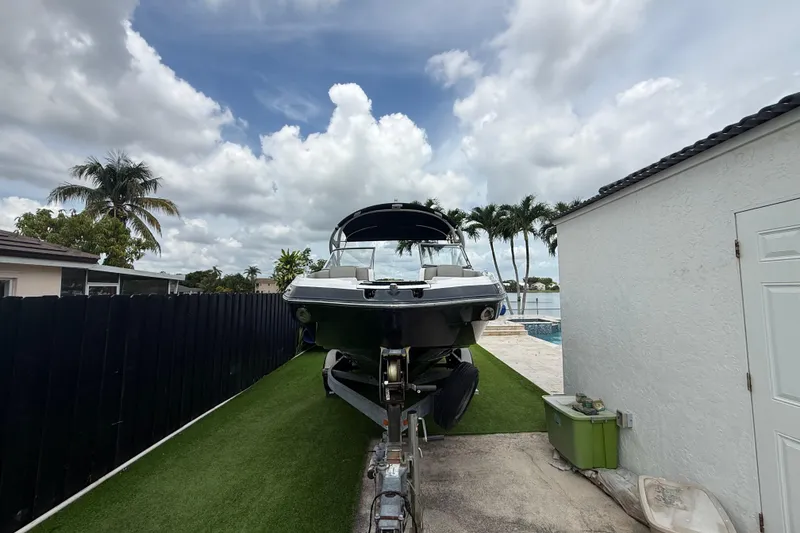 Slide: The Image of 2012 Yamaha Boats 242 Limited S on trailer, parked beside a house with palm trees. - 28