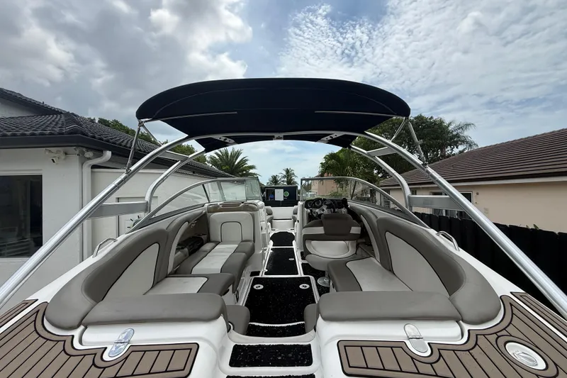 Slide: The Image of 2012 Yamaha Boats 242 Limited S with sleek seating and canopy, parked outdoors. - 8