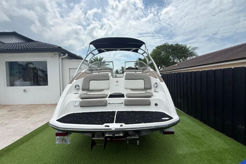 Slide: The Image of 2012 Yamaha Boats 242 Limited S on grass, showcasing rear view and seating area. - 2
