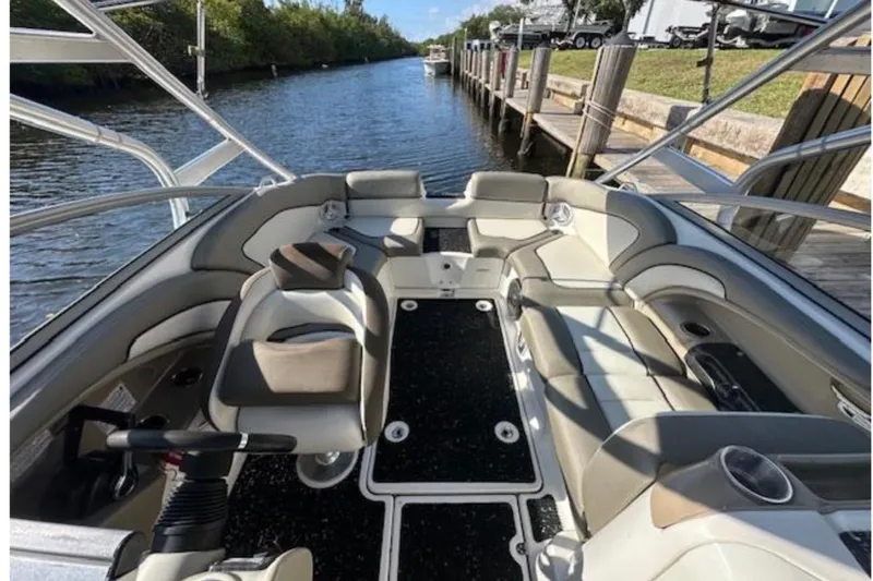 Slide: The Image of 2012 Yamaha Boats 242 Limited S interior with seating, docked by a scenic waterway. - 9