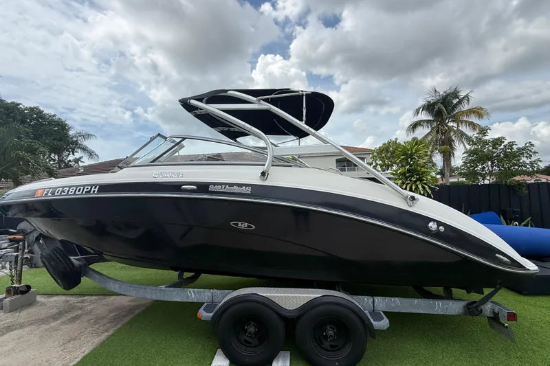 Slide: The Image of 2012 Yamaha Boats 242 Limited S on trailer, under cloudy sky, surrounded by palm trees. - 1