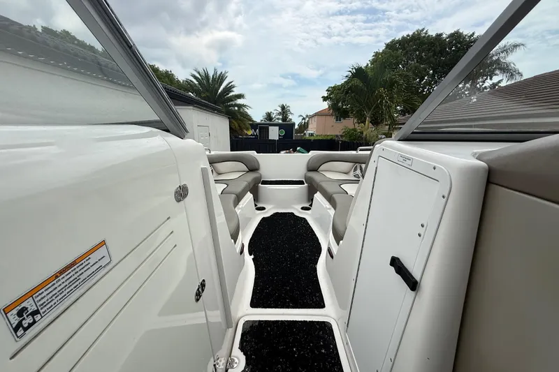Slide: The Image of 2012 Yamaha Boats 242 Limited S interior with seating and storage, surrounded by tropical greenery. - 18