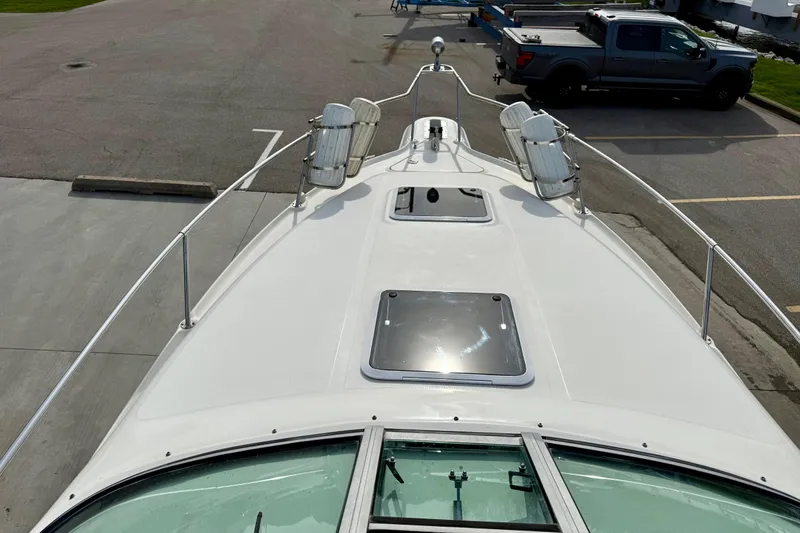 Slide: The Image of 1997 Sea Ray 270 Sundancer boat deck with hatches, docked near a truck. - 9