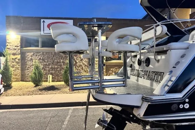 Slide: The Image of 1995 Maxum 2700 SR boat with custom bar stools on the deck, parked near a building. - 13