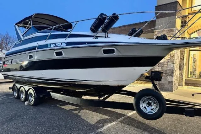 Slide: The Image of 1995 Maxum 2700 SR boat on a trailer, parked outdoors near a building. - 3