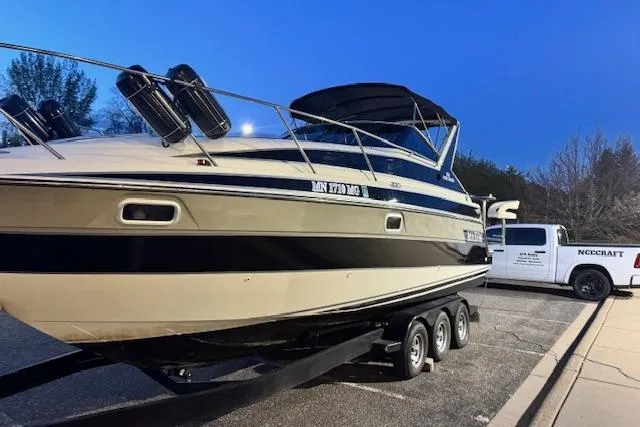 Slide: The Image of 1995 Maxum 2700 SR boat on trailer, parked beside a white truck at dusk. - 4
