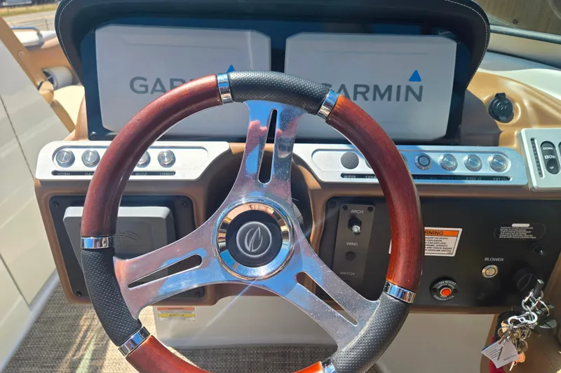 Slide: The Image of 2021 Crownline Eclipse E235 dashboard with Garmin displays and wooden steering wheel. - 13