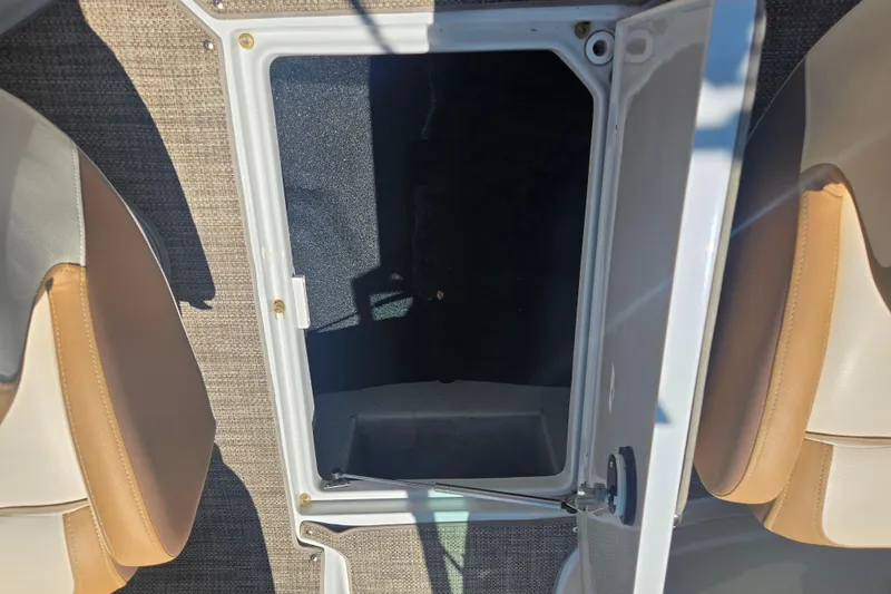 Slide: The Image of 2021 Crownline Eclipse E235 boat storage compartment with open hatch and beige seating. - 27