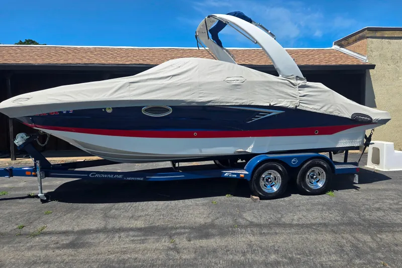 Slide: The Image of 2021 Crownline Eclipse E235 boat on trailer, covered, parked outdoors. - 28