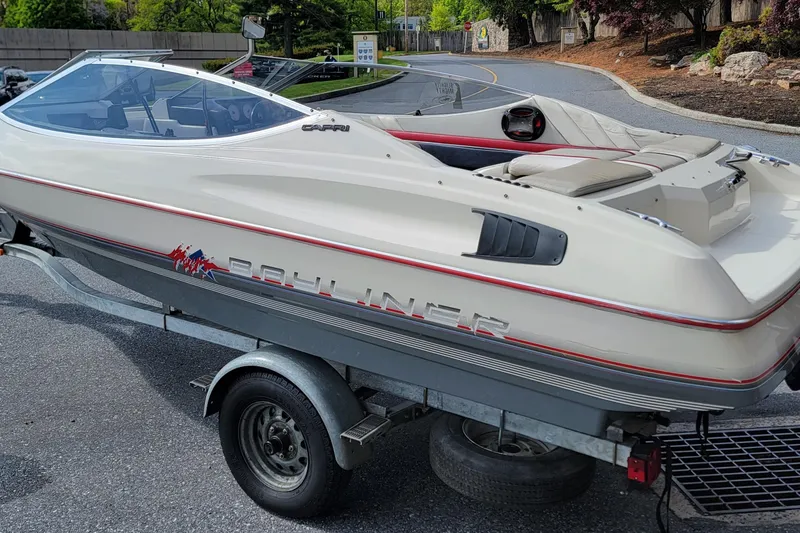 The Image of 1990 Bayliner 1850 Capri boat on trailer, parked on a paved road. - 0