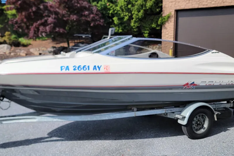 Slide: The Image of 1990 Bayliner 1850 Capri boat on trailer, parked outdoors with trees in background. - 1
