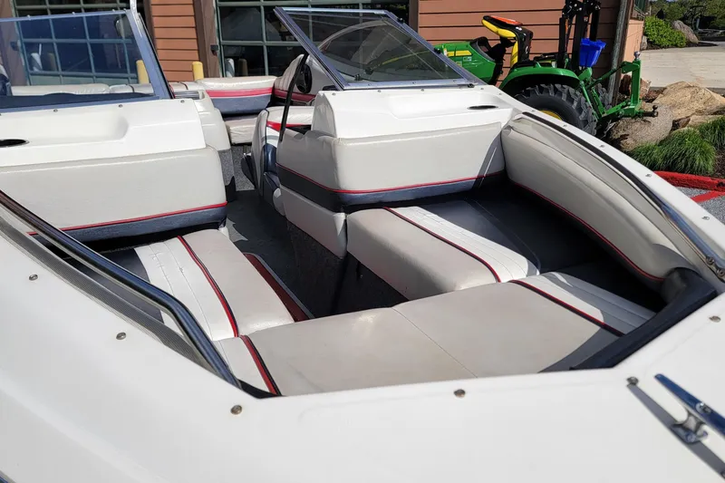 Slide: The Image of 1990 Bayliner 1850 Capri boat interior with white and red seating, parked outdoors. - 5