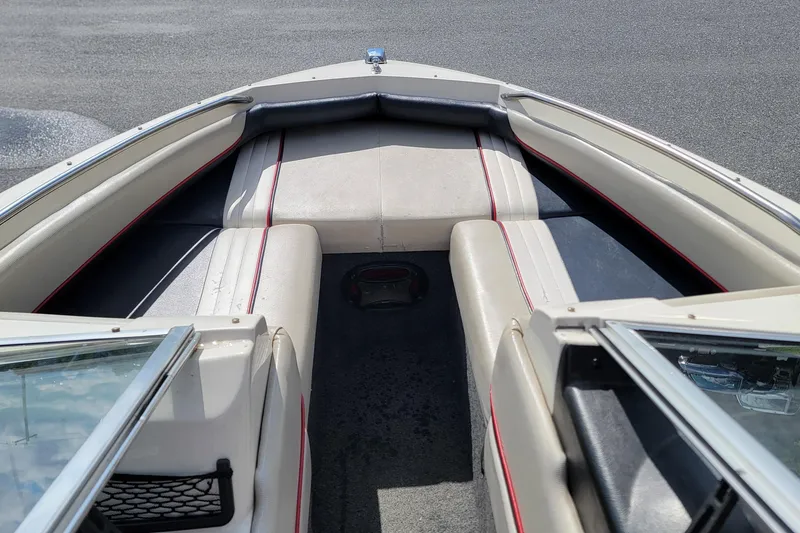 Slide: The Image of 1990 Bayliner 1850 Capri boat interior with beige seating and red accents. - 9