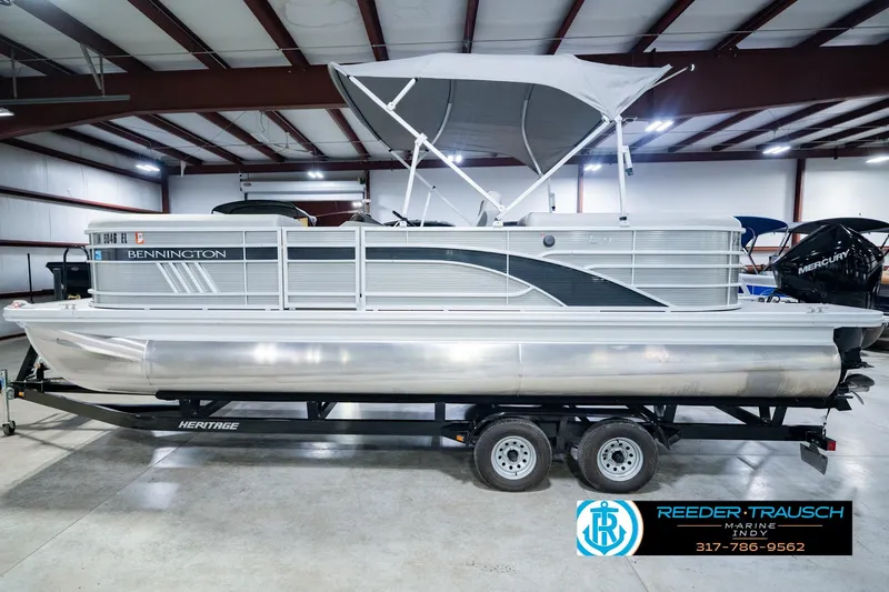 Slide: The Image of 2023 Bennington 23 LSR pontoon boat with canopy, displayed indoors on a trailer. - 12