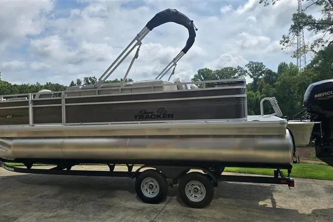 Slide: The Image of 2026 Sun Tracker Fishin' Barge 22 DLX pontoon boat on trailer, parked outdoors. - 1