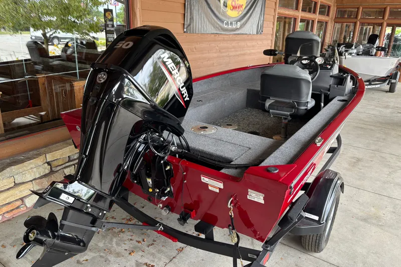 Slide: The Image of 2026 Tracker Super Guide V-16 SC boat with Mercury engine, red exterior, parked outdoors. - 5