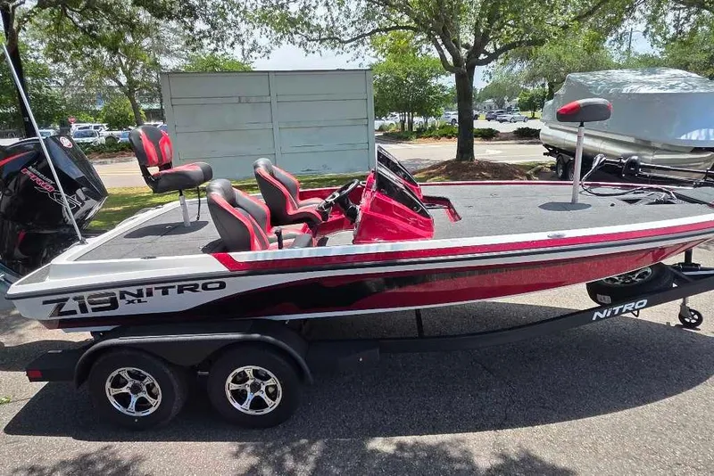 The Image of 2026 Nitro Z19 XL boat with red and black design on a trailer, parked outdoors. - 0