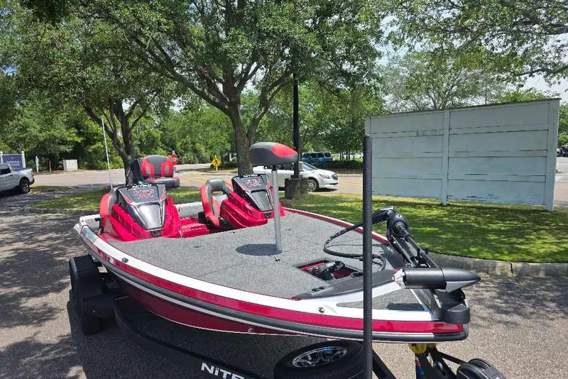 Slide: The Image of 2026 Nitro Z19 XL boat with red accents parked outdoors under trees. - 3