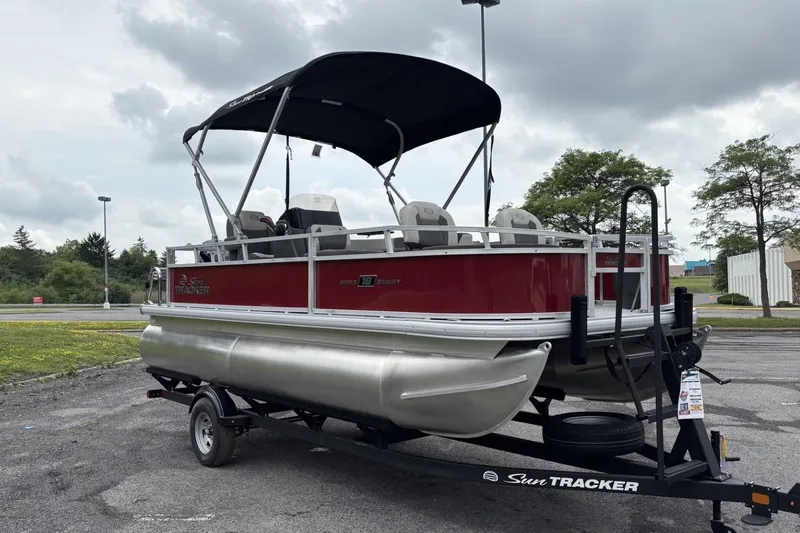 Slide: The Image of 2026 Sun Tracker Bass Buggy 18 DLX pontoon boat on trailer, parked outdoors. - 1