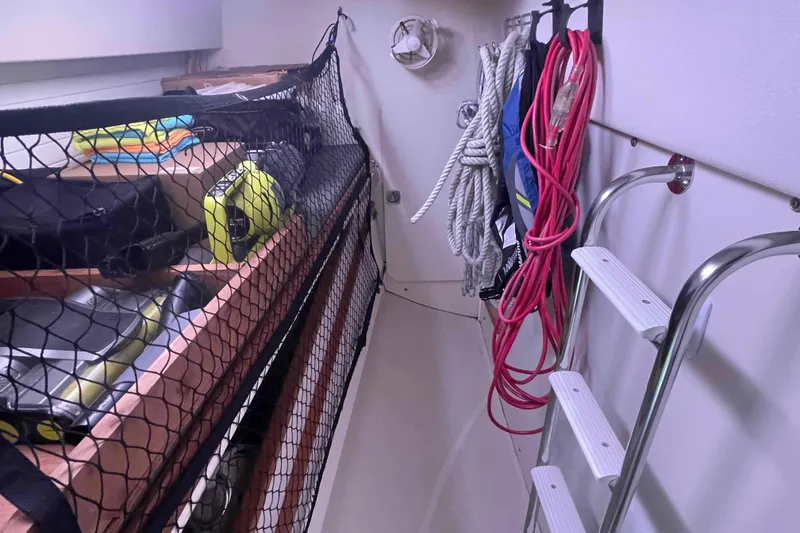 Slide: The Image of Storage area in a 2013 Catalina Morgan 440 sailboat with ropes, ladder, and netted shelves. - 25